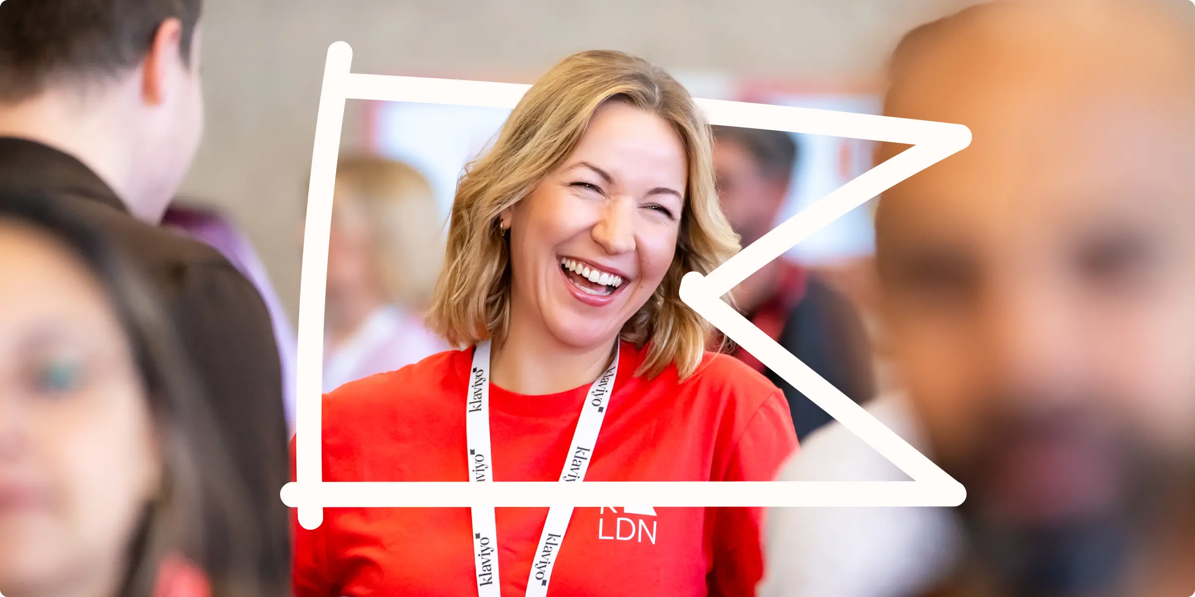 A smiling Klaviyo employee at a K:LDN, a Klaviyo event in London. A freeform outline of Klaviyo's flag mark frames her face.